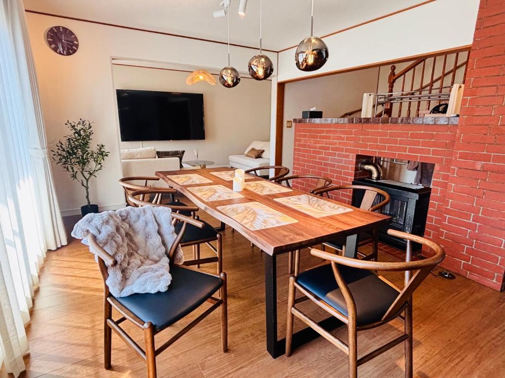 a dining room with a wooden table and chairs at Snoa Kitanomine - スノア キタノミネ - in Furano