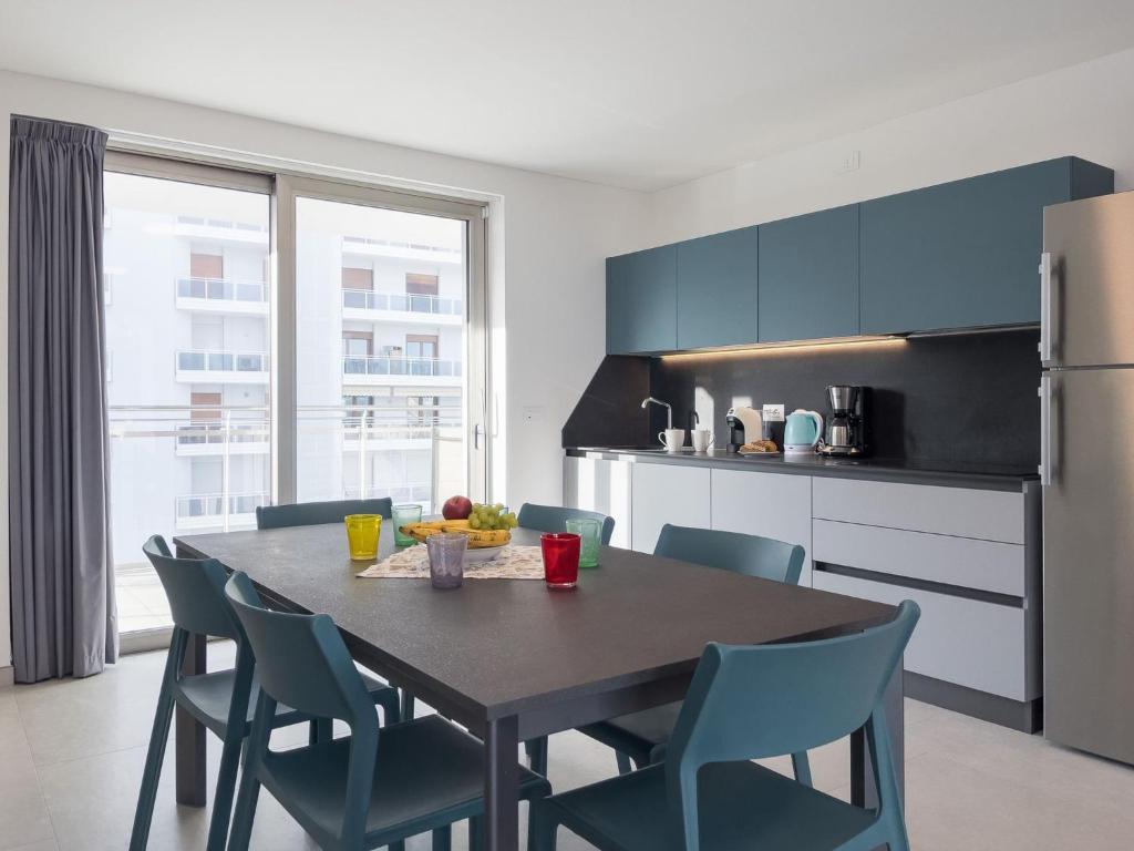 a kitchen with a table and chairs and a refrigerator at Modern flat in Piazza Fontana in Lignano Sabbiadoro