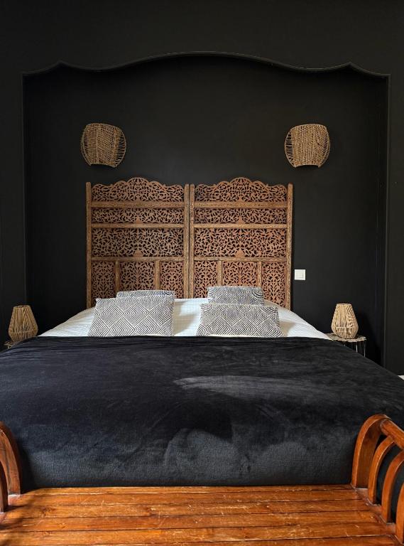 a bedroom with a large bed with a wooden headboard at Hotel du Pot d'Etain in Chalons en Champagne