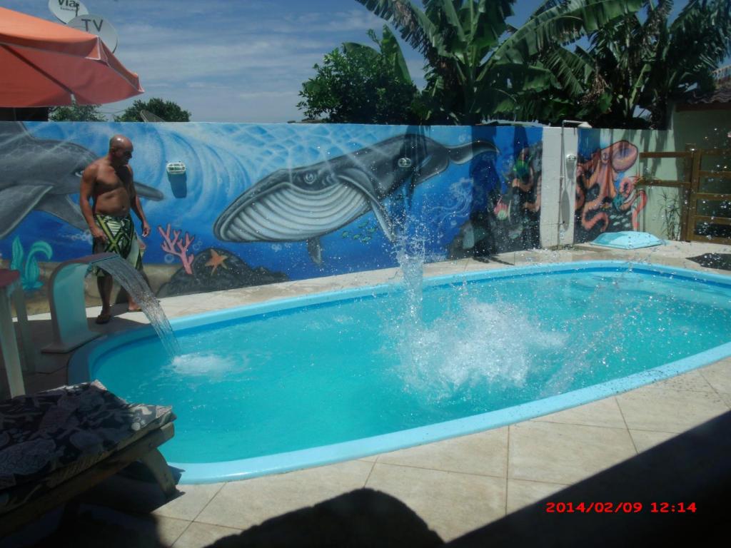 a man playing in a pool with a dolphin mural at Residencial Campo Dunna in Praia do Rosa