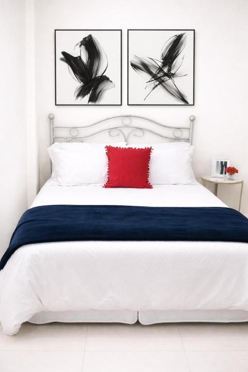 a bedroom with a white bed with a red pillow at PINK POUI Spaces Vacation Rentals in Arima