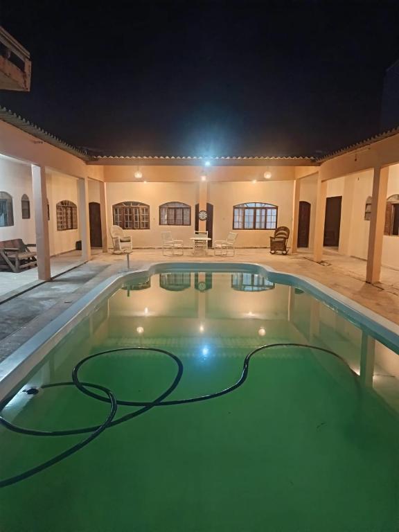 a swimming pool at night with a hose in the water at Pousada e hostel Braga in Itanhaém