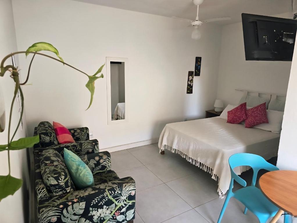 a room with a bed and a couch and a table at Suites Nativa in Ubatuba