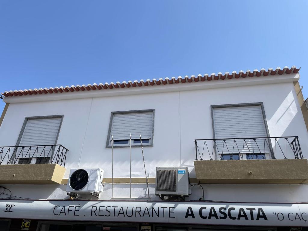 a white building with two balconies and a sign on it at Alojamento A Cascata in Vidigueira