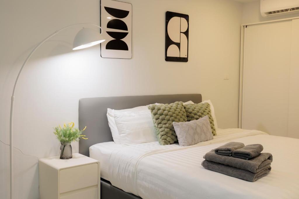 a bedroom with a bed with towels on it at Elegant Modern White Suite in Chiang Mai