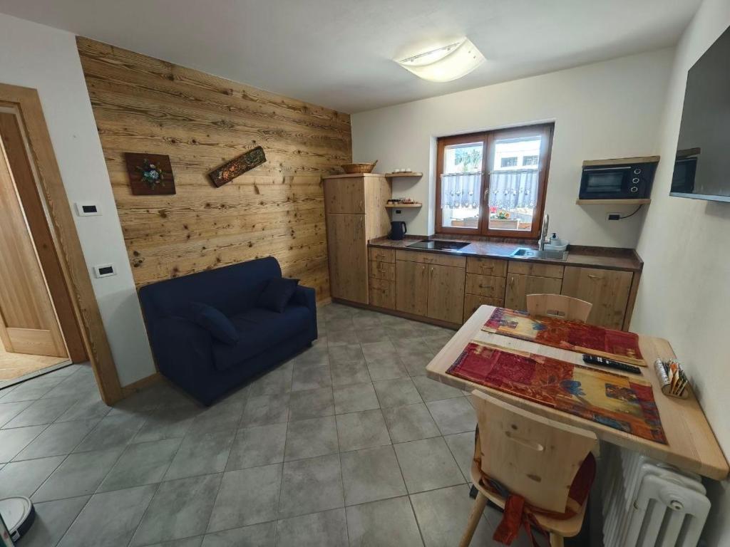 a living room with a blue couch and a kitchen at MB Appartamento in Santo Stefano di Cadore