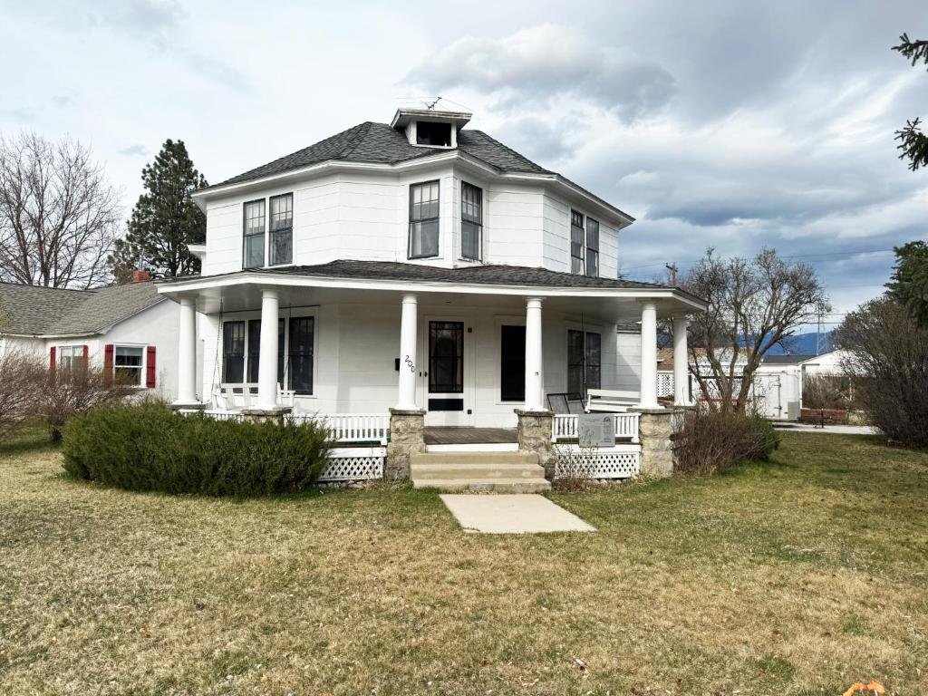 a white house with a porch and a yard at Historic 1908 Wamsley House-Completing Renovation! in Hamilton
