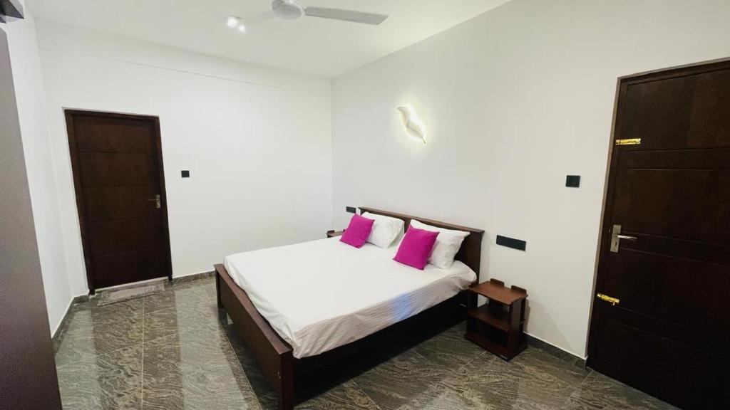 a bedroom with a bed with two pink pillows at Seaside Residence Negombo in Negombo