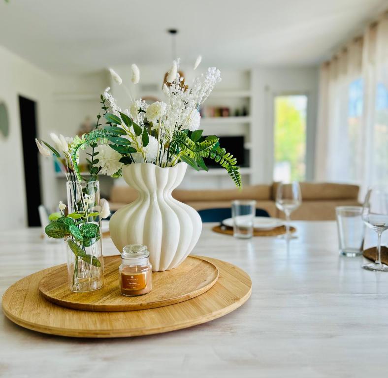 a table with a white vase with flowers in it at Le Cottage de L&M in Sigean