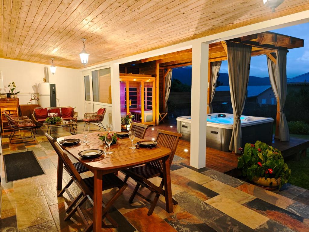 a dining room and living room with a table at La Kaz 57 - Maison avec jacuzzi et sauna - La Réunion in La Plaine des Palmistes