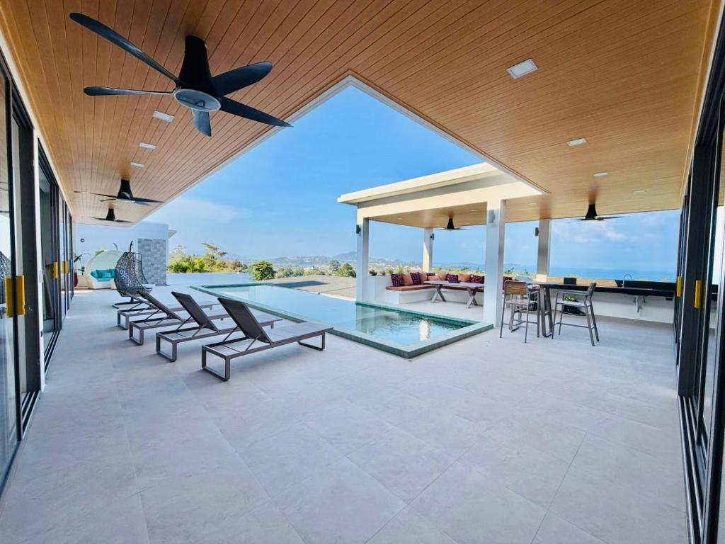 an outdoor patio with chairs and a ceiling fan at Villa luxurious in Koh Samui