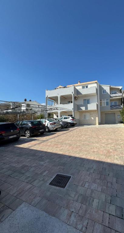 a parking lot with cars parked in front of a building at Apartment Ivan in Kastel Sucurac