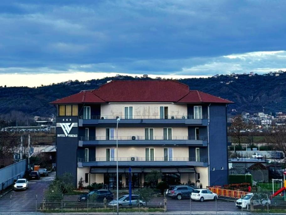 a large building with a red roof in a parking lot at Hotel Verzaci in Rinas