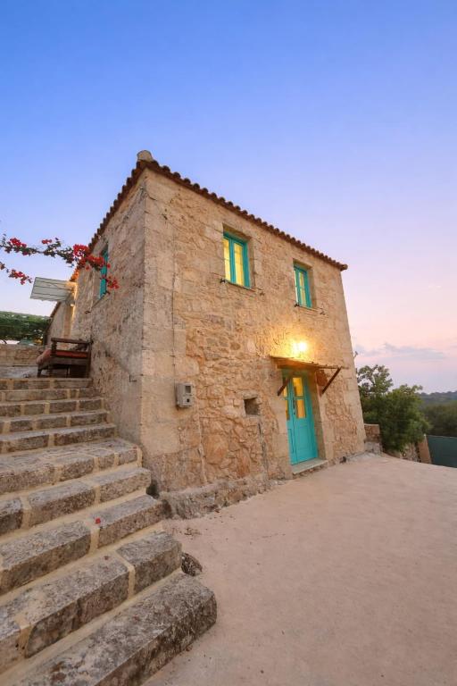 a stone building with a blue door and stairs at Light & Stone Villa, Kefalonia in Lixouri