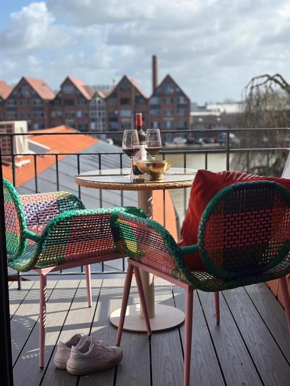 two chairs and a table with wine glasses on a balcony at Hafen33 in Leer