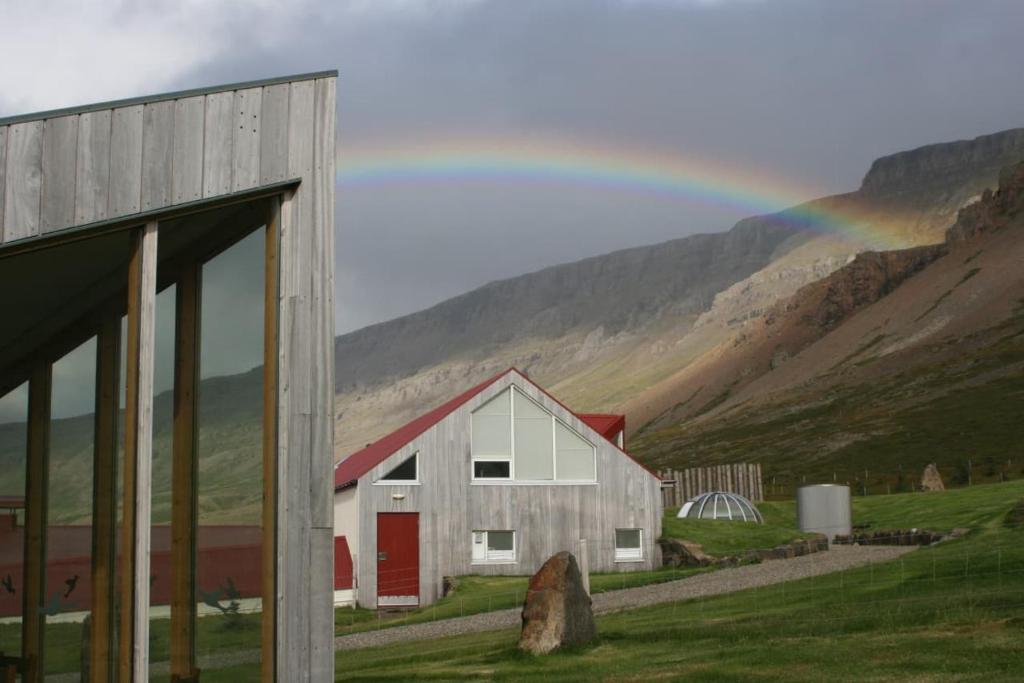 a painting of a barn with a rainbow in the background at Silfurberg in Þorgrímsstaðir