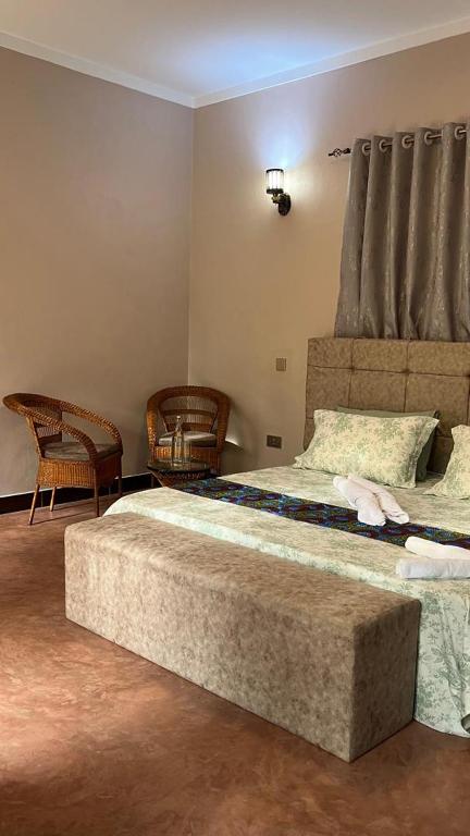 a bedroom with two beds and two chairs at Katojo Quick Rides and stays in Arusha