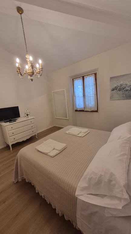 a bedroom with a bed and a television and a chandelier at La Perla del Boccaccio in Certaldo