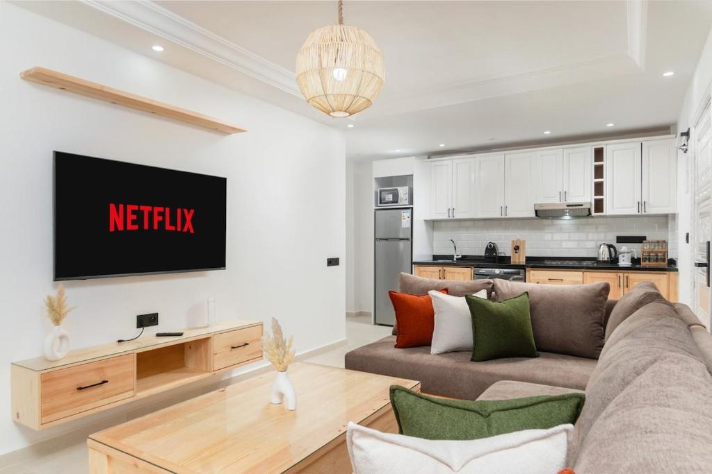 a living room with a couch and a tv on a wall at Taghazout Bay Chic Residence Sea View in Tamraght Ouzdar
