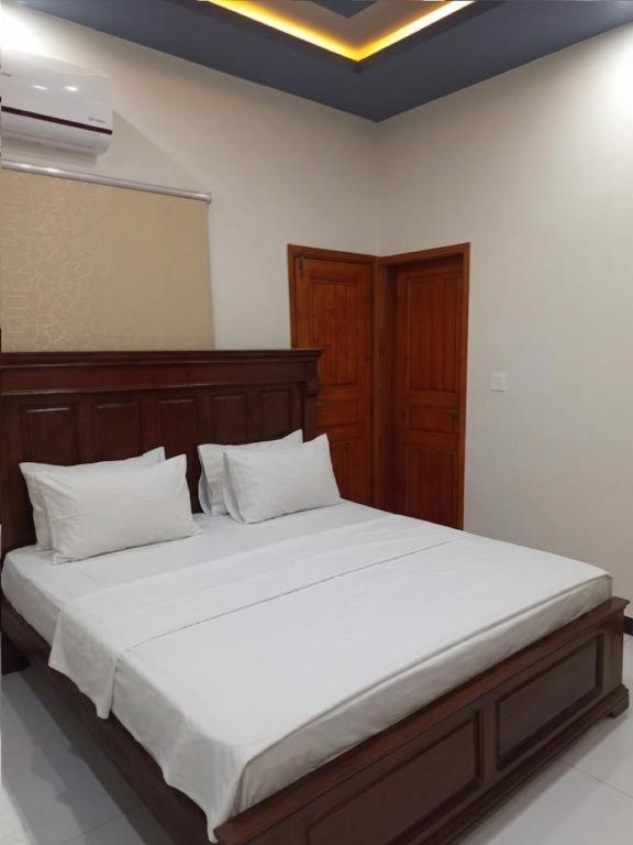 a bedroom with a large bed with white sheets at Nursery Suites in Karachi