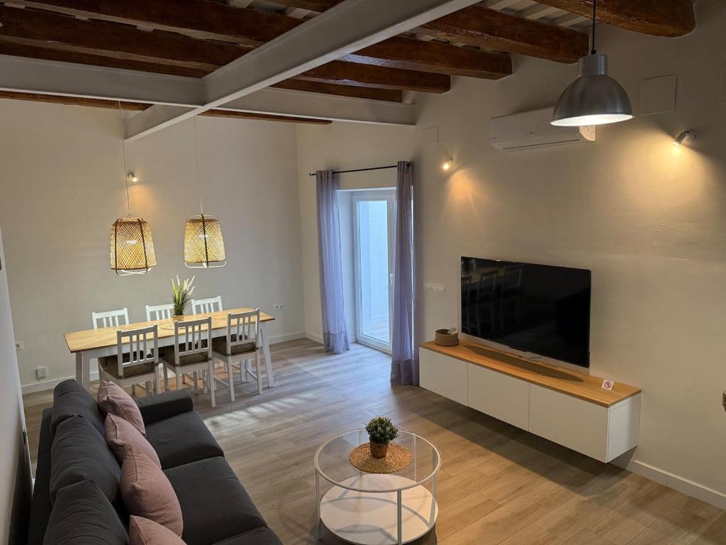 a living room with a couch and a tv and a table at Casa Centenaria 1769 in Cubelles