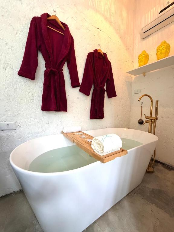a white bath tub with red coats hanging on a wall at Studio Bali - Village Capixaba in Gravatá