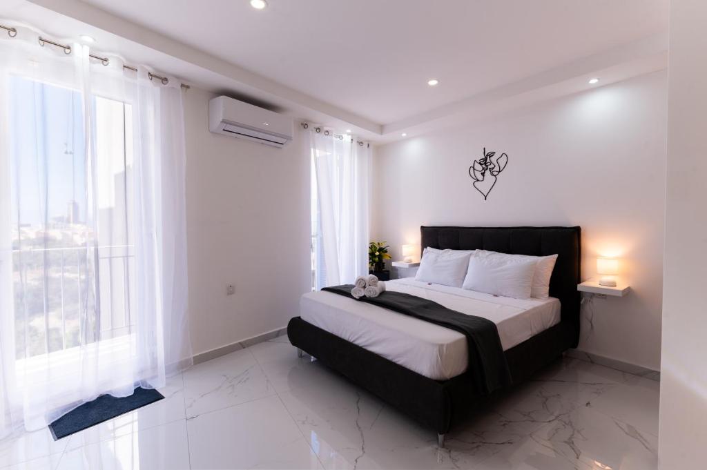 a bedroom with a large bed with white walls and windows at Stylish place in St Julians in St. Julianʼs