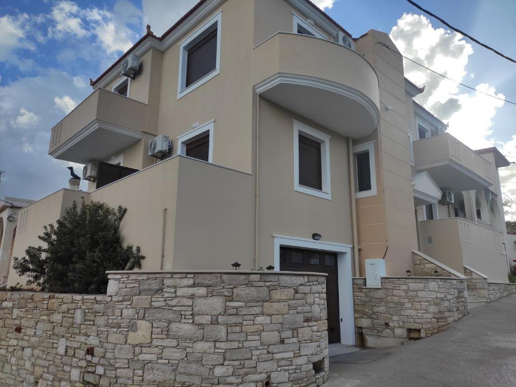 a large white building with a stone wall at Varkaris Room 2 in Katarráktis