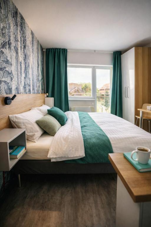 a bedroom with a large bed with green curtains and a window at Apartmán Lenka in Veľký Meder