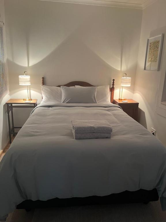 a large white bed with two lamps on two tables at The Red door cottage in Pretoria