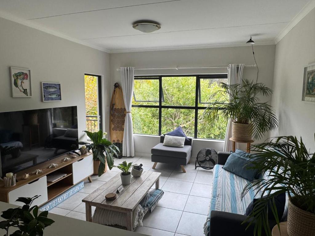 a living room with plants and a large window at The Zhen in Strand