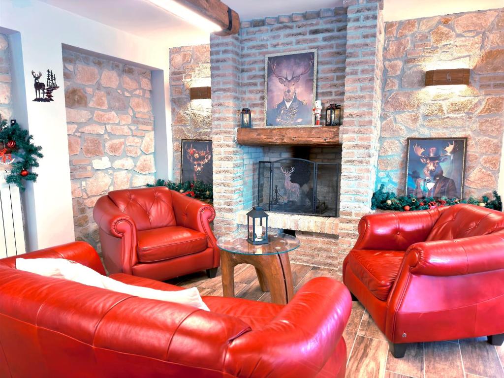 a living room with red leather furniture and a stone fireplace at La Baita Del Cervo 2 in Castel di Sangro
