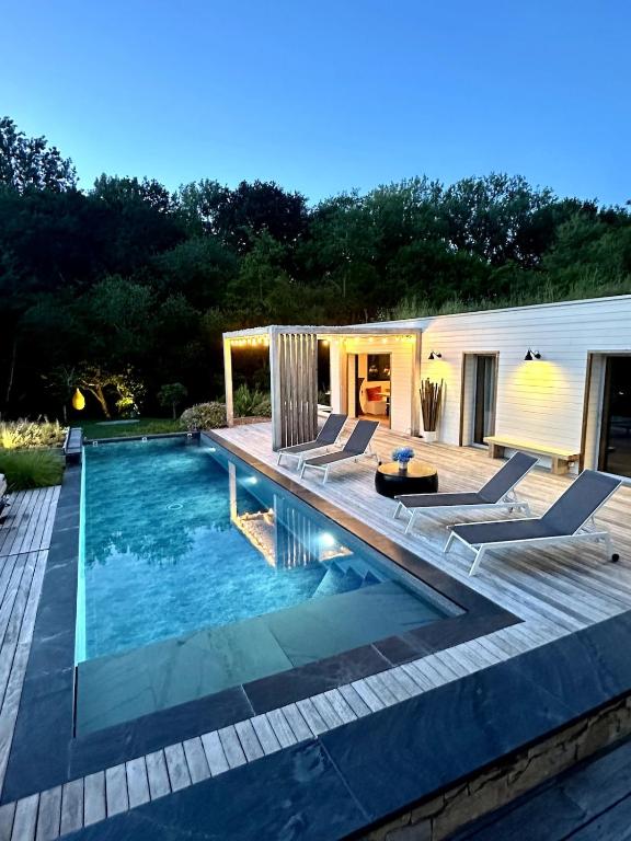 a swimming pool with a deck and chairs in a backyard at Small house with swimming pool and jacuzzi in Biarritz