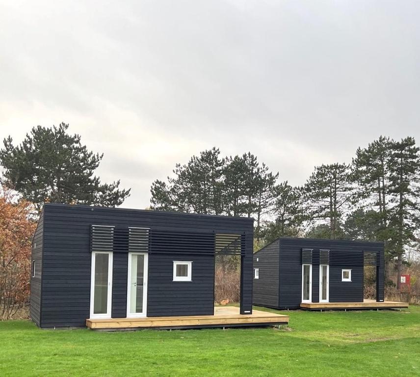 a black house with white windows on a green field at DCU-Camping Kulhuse in Kulhuse