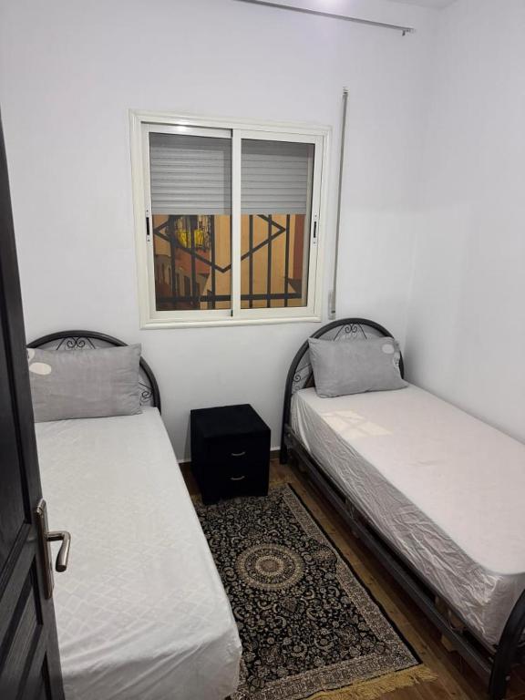 two beds in a room with a window at Dar yasmine in Azrou