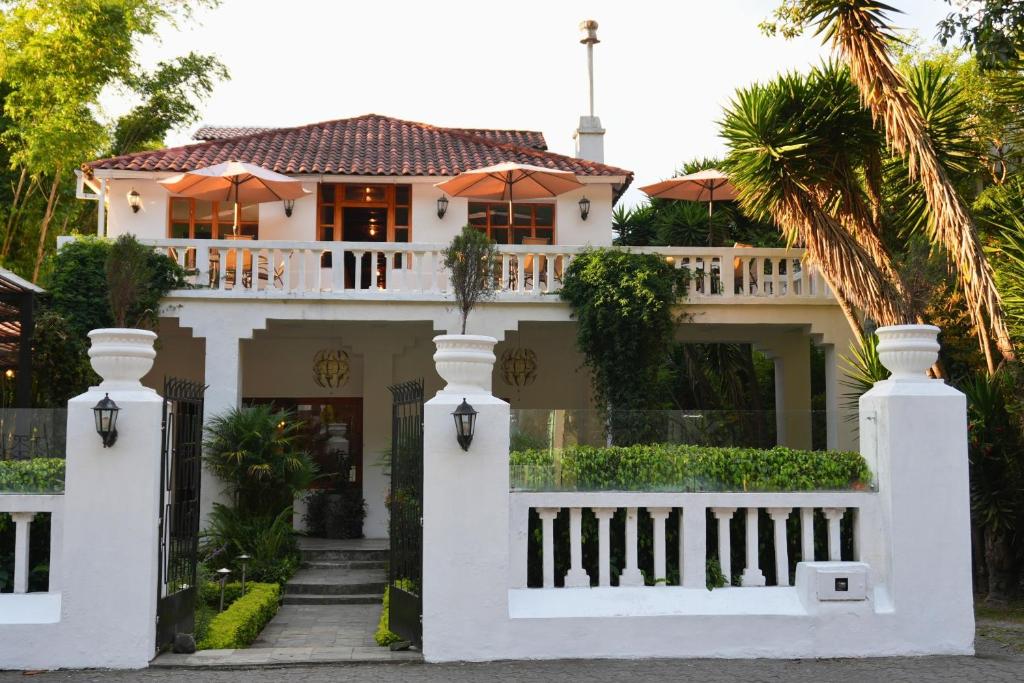 a white house with a white fence and palm trees at 593 Hotel Boutique Baños in Baños