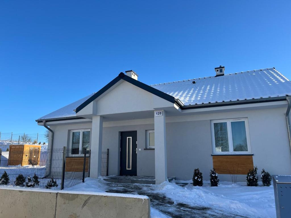 a small white house with snow on the ground at DOM LAGOWSKI z SAUNA in Łagów