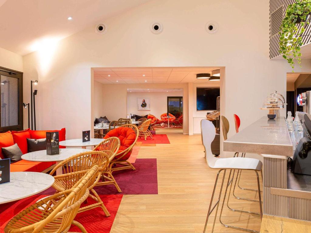a living room with tables and chairs and a kitchen at ibis Tours Sud in Chambray-lès-Tours