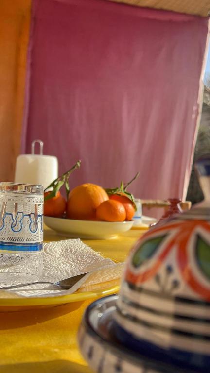 a table with a plate of oranges on a table at Traditional nomad camp in Merdani