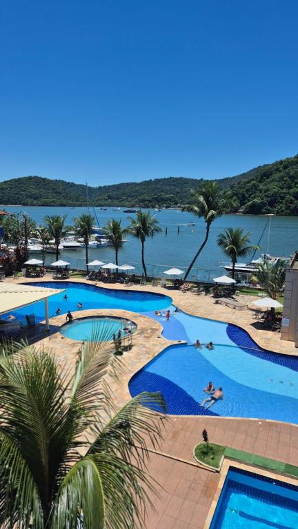 a large swimming pool next to a body of water at Apart Itacuruçá - Hotel Porto Marina in Mangaratiba