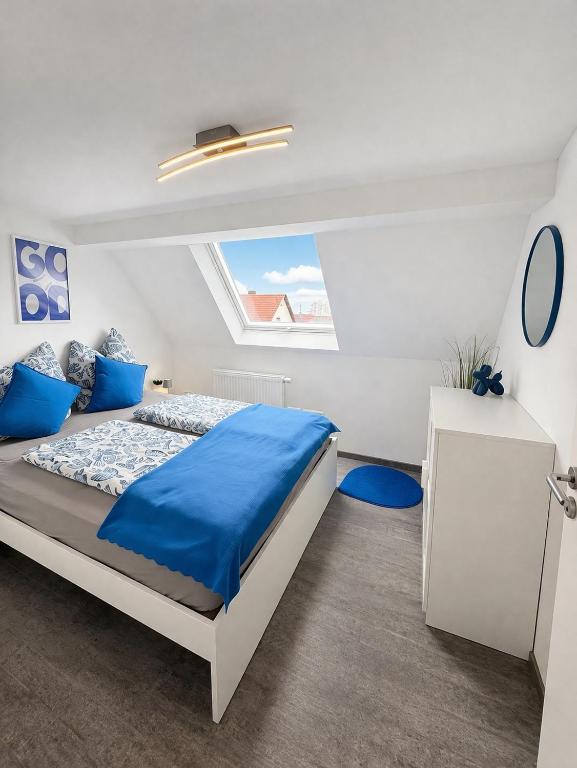 a white bedroom with a blue bed and a window at Family & Work Apartment in Schopfloch