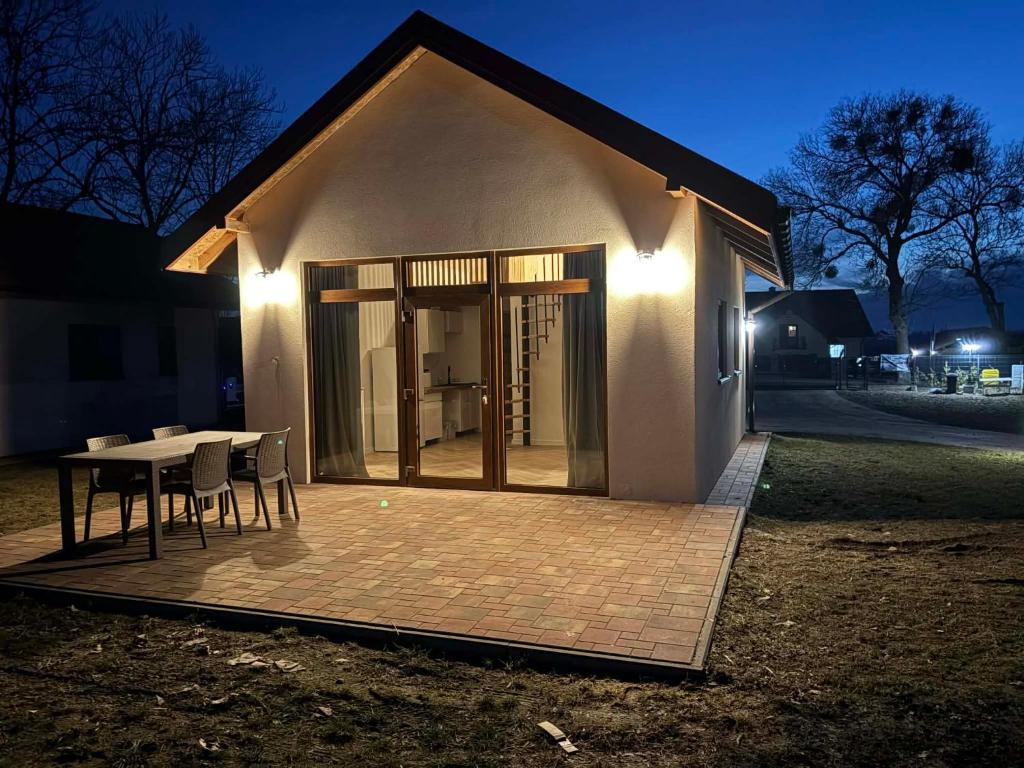 a small house with a table and chairs at night at Domki Mazury Mikołajki in Mikołajki