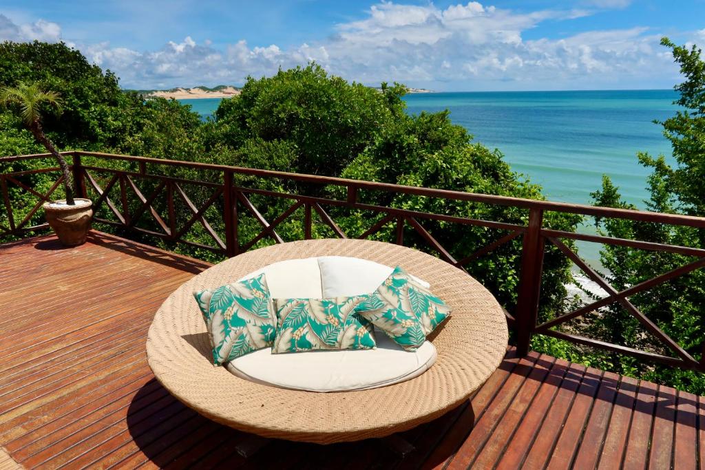 a wicker chair sitting on a deck with the ocean at Porto Brasil Resort - Casa de praia em condomínio de luxo in Parnamirim
