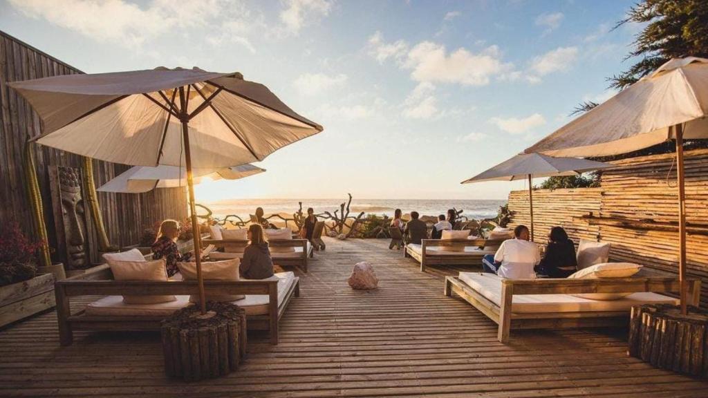 a group of people sitting on a deck with umbrellas at Hotel 8 al Mar in Pichilemu