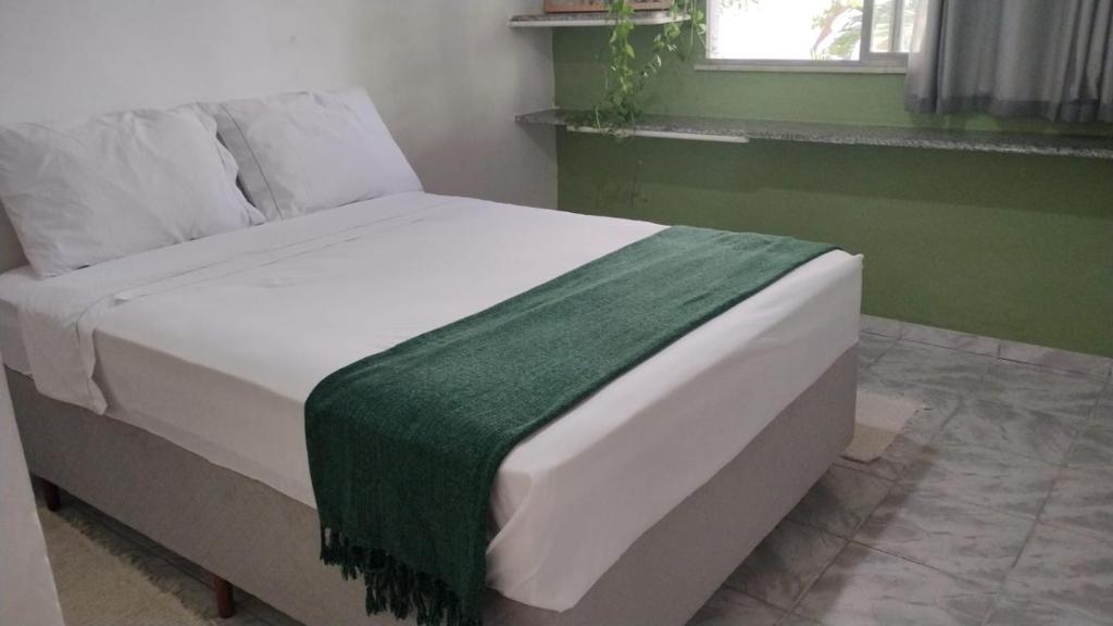 a bed with a green and white blanket on it at Quarto privativo em casa compartilhada in Aracaju