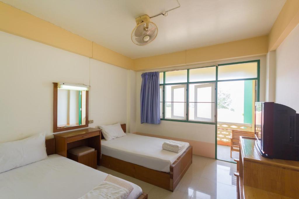 a room with two beds and a tv and a window at Mont Talay Hotel in Prachuap Khiri Khan