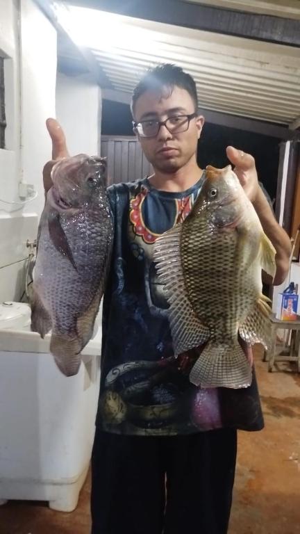 a man holding two fish in his hands at pousada recanto gerais in Carmo do Rio Claro