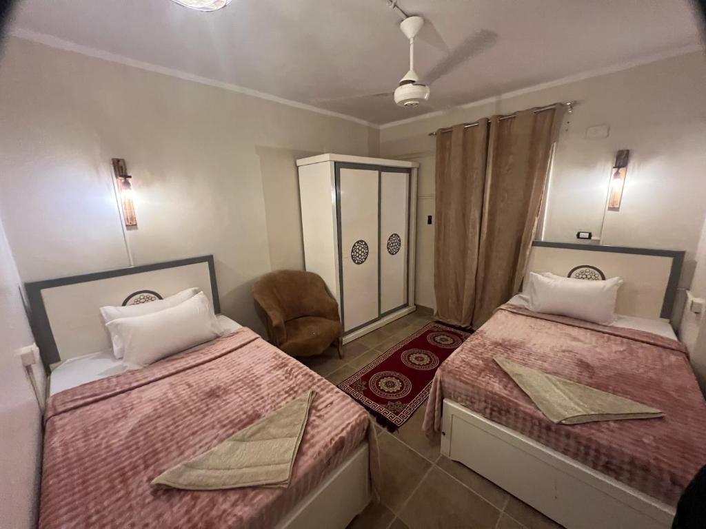 a bedroom with two beds and a chair at Backpacker Room 2 in Aswan