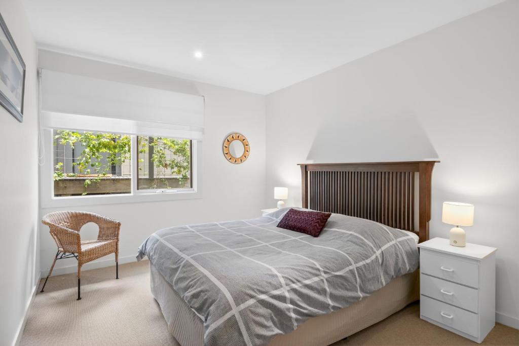 a bedroom with a bed and a chair and a clock at Breakers Holiday House in Lorne