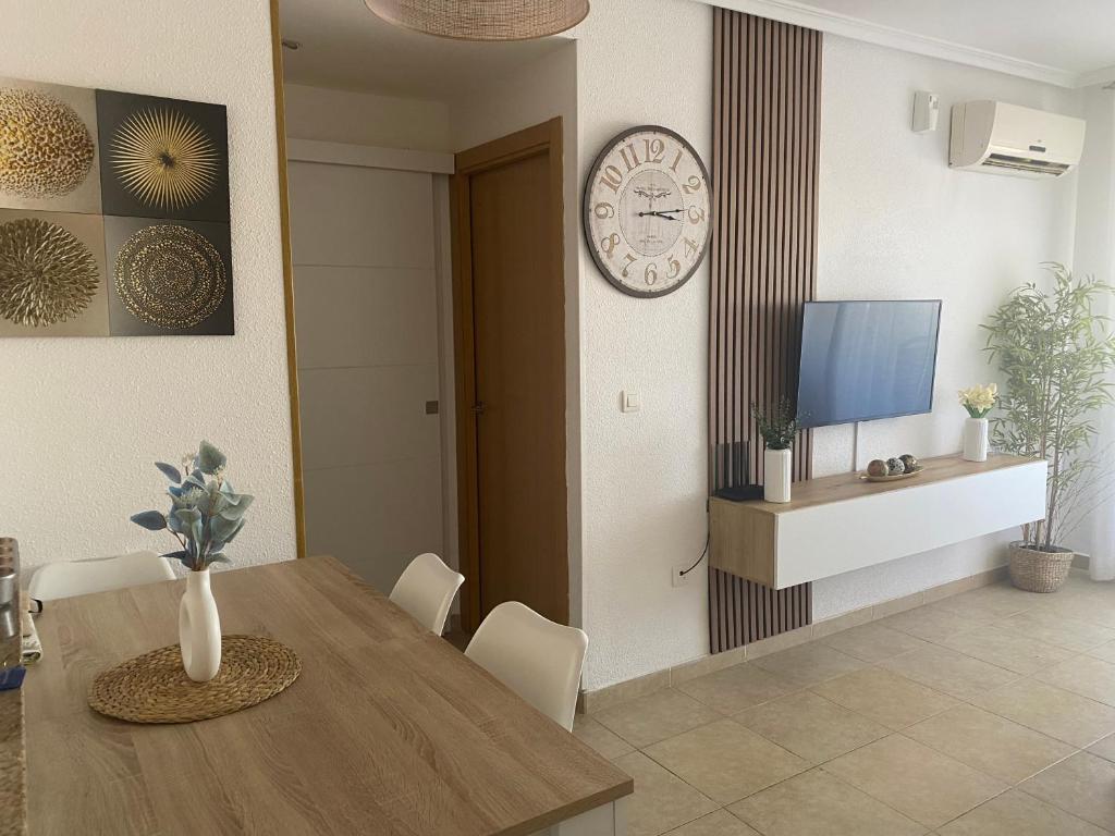 a dining room with a table and a clock on a wall at Edificio TORREMAR vistas al mar, orientación norte, Wifi y Smart-TV in Oropesa del Mar